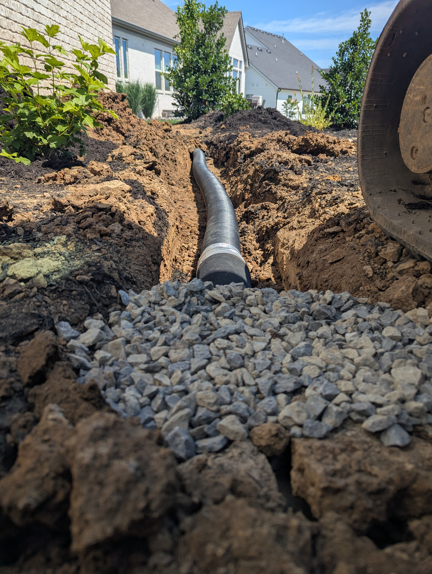 Targeted French drain installation with perforated pipe and stone backfill in a Franklin TN landscape bed