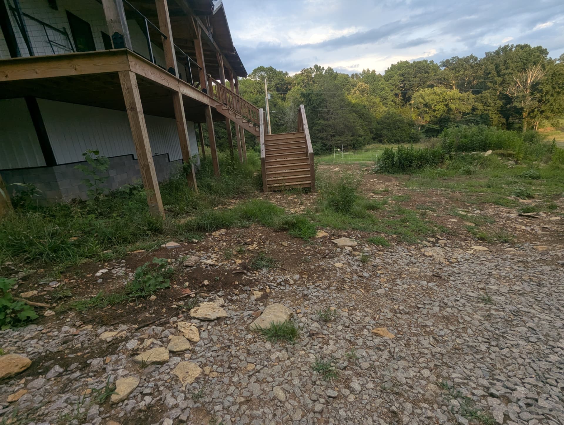Unfinished rocky grade beside barndominium stairs before drainage correction